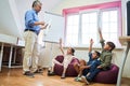 All of the children sitting in classroom with raising hands