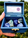 All Colour Colors CHAKRA INDIGO BLEU CROWN Gemstone Polished Hand Palmstones Rocks in wooden Box Near Water Spiritual Royalty Free Stock Photo