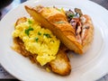 All-Day breakfast / brunch meal platter of scrambled eggs; croissant; sausage; bacon and mushrooms on a white plate Royalty Free Stock Photo