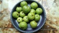 A Bunch Guavas fruit with green color on a gray tray circle, in the room