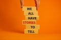 We all have stories to tell symbol. Wooden blocks with words `We all have stories to tell`. Businessman hand. Beautiful orange