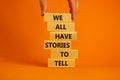 We all have stories to tell symbol. Wooden blocks with words `We all have stories to tell`. Businessman hand. Beautiful orange