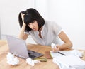 All her work has amounted to nothing. A shocked businesswoman looking at her laptop screen amidst crumpled documents.