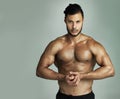 All his hard work has paid off. Studio shot of an athletic young man flexing his muscles against a gray background. Royalty Free Stock Photo