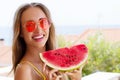 All Inclusive Cheap Summer Holidays. Young Happy Woman with Watermelon and pink sunglasses at beach Background. Summertime fun Royalty Free Stock Photo