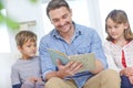 And they all lived happily ever after. a father reading a story to his son and daughter at home.