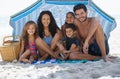 They all love the beach. A happy family smiling at the camera while sitting under an umbrella at the beach. Royalty Free Stock Photo