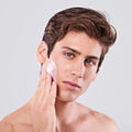 All man and all smooth. Studio shot of a handsome bare chested young man applying lotion to his face.