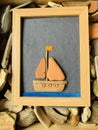 Pebble art with framed picture of a boat floating on water made of river stones Royalty Free Stock Photo