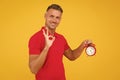 All right. Happy man hold alarm clock showing OK sign. Punctuality and accurate timekeeping. Chronometry and timekeeping Royalty Free Stock Photo