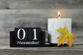 All Saints Day. Burning candle, wooden calendar and yellow autumn leaf Royalty Free Stock Photo