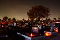 All Saints Day in cemetery. Flowers and lighted candles on graves near church at night. Graveyard in autumn. Many burning candles. Royalty Free Stock Photo