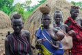 All women with their infants in bright clothes posing to the tourists in the local Mursi tribe village