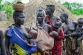 All women with their infants in bright clothes posing to the tourists in the local Mursi tribe village