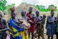 All women with their infants in bright clothes posing to the tourists in the local Mursi tribe village