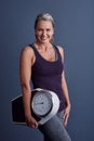 All you need is a goal and a scale. Studio portrait of an attractive mature woman holding a weightscale against a blue Royalty Free Stock Photo