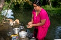 Alleppey, India - 22 september 2019: adult indian woman doing daily chores in rural india washing dishes by the river with Royalty Free Stock Photo