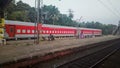 An Indian Railways train painted red parked on a platform of a railway station