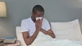 Allergic Young African Man Sneezing in Bed