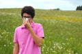 Allergic boy with glasses and pink t-shirt blows his nose Royalty Free Stock Photo