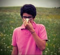 Allergic boy with glasses and pink t-shirt blows his nose Royalty Free Stock Photo
