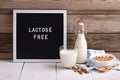 Allergic food concept. Almond milk in bottle and glass, bowl with almonds scattered around and letter board with text LACTOSE FREE