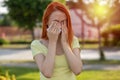 Allergies make trouble - pain in eyes. Young redhair woman sneezing. Pollen Allergy symptoms Royalty Free Stock Photo