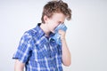 Allergy Boy Child with runny nose holding a handkerchief. Teenager is having bad health and standing on white studio background al Royalty Free Stock Photo