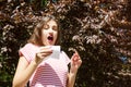 Allergy concept. Sneezing young girl with nose wiper among blooming trees in park Royalty Free Stock Photo