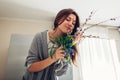 Allergy free. Happy woman smelling bouquet of flowers after recovery on kitchen. Seasonal allergy concept Royalty Free Stock Photo