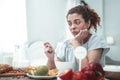 Curly woman sitting in kitchen having allergy to peanuts