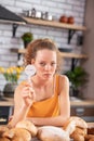 Miserable young woman with light eyes leaning on wooden table