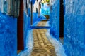 Alley in blue city of chefchauen with doors in daylight