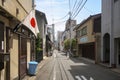An alley in downtown Kyoto with small houses and electrical network cable. The national flag of Japan or hinomaru on one of the ho