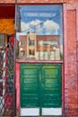 Alley large double green doors with glass display above along red brick wall