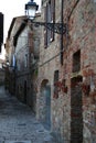 Alley of a medieval stone buildings with old wall lamp in Tuscan village, Italy Royalty Free Stock Photo