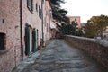 An alley of a medieval village with ruined brick houses and a walking tourist Marche, Italy