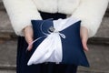 alliances wedding rings on white blue pillow in bride hands for the marriage couple