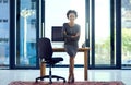 Allow me to share my success story with you. Portrait of a confident young businesswoman leaning against a desk at work. Royalty Free Stock Photo