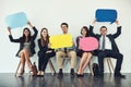 Allow us to introduce ourselves. Studio shot of a group of businesspeople holding colorful speech bubbles while waiting