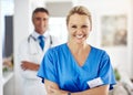 Allow us to take care of you. Portrait of a female nurse standing with her arms crossed in the hospital with a male Royalty Free Stock Photo