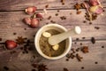 Allspice in a ceramic mortar and scattered garlic cloves, star anise and allspice on a wooden table. Close up Royalty Free Stock Photo