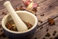 Allspice in a ceramic mortar and scattered garlic cloves, star anise and allspice on a wooden table. Close up Royalty Free Stock Photo