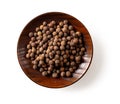 Allspice pimento berries on a brown wooden plate isolated on a white background. Jamaica pepper grains on a saucer for cooking. Royalty Free Stock Photo