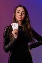 Brunette woman in black velvet dress showing two playing cards, posing against coloful background. Gambling Royalty Free Stock Photo