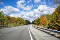 An alluring landscape with a highway stretching into the horizon framed by picturesque autumn maples in the state of Massachusetts Royalty Free Stock Photo