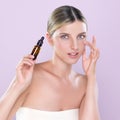 Alluring portrait of beautiful woman applying CBD oil as facial skincare concept