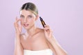 Alluring portrait of beautiful woman applying CBD oil as facial skincare concept