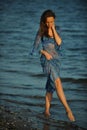 Alluring woman posing on the beach in floral transparent dress.