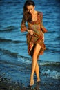 Alluring woman posing on the beach in floral transparent dress.